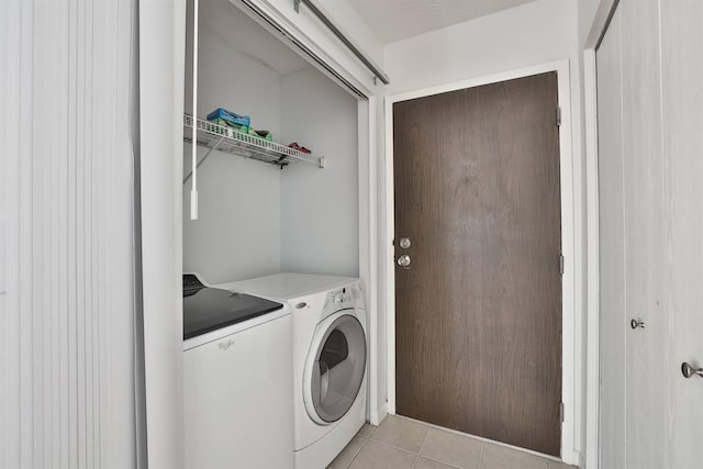 laundry area featuring washing machine and clothes dryer and light tile patterned flooring