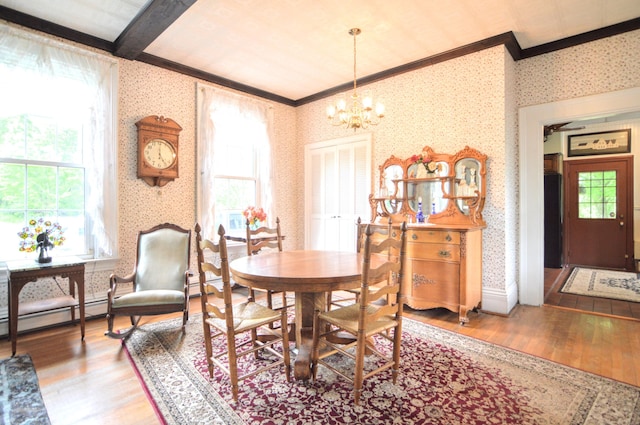 dining space featuring wood-type flooring, crown molding, a wealth of natural light, and a chandelier