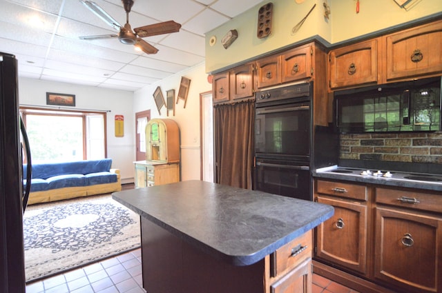 kitchen with ceiling fan, a center island, dark tile patterned floors, a paneled ceiling, and black appliances