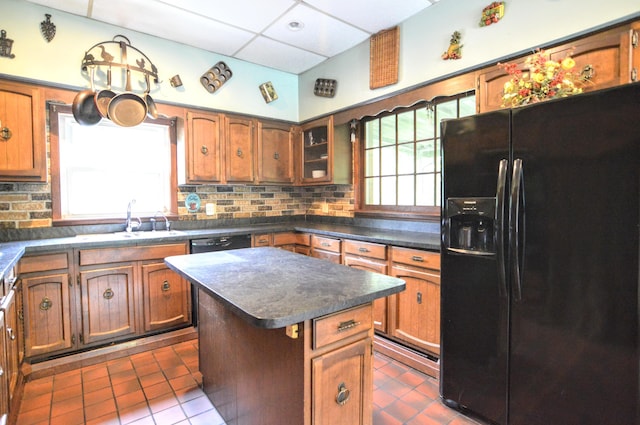 kitchen featuring backsplash, black appliances, dark tile patterned flooring, sink, and a kitchen island