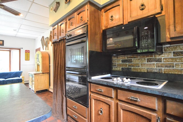 kitchen featuring backsplash, a drop ceiling, a baseboard heating unit, black appliances, and dark tile patterned flooring