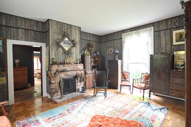 living room with a brick fireplace, wood walls, and parquet flooring