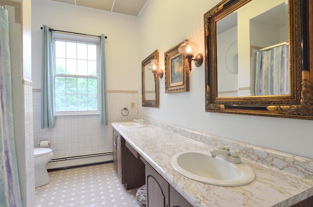 bathroom featuring vanity, toilet, tile walls, and a baseboard heating unit