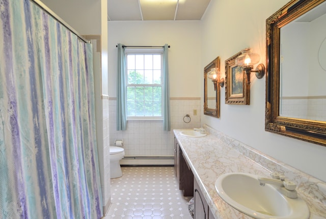 bathroom with baseboard heating, tile patterned floors, toilet, vanity, and tile walls