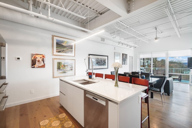 kitchen featuring a kitchen island with sink, sink, hardwood / wood-style flooring, dishwasher, and white cabinetry