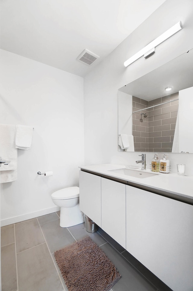 bathroom featuring tile patterned floors, vanity, a tile shower, and toilet