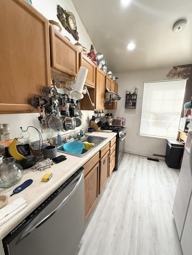 kitchen featuring stainless steel appliances, extractor fan, light hardwood / wood-style floors, and sink