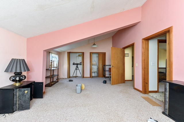 living room with a textured ceiling, light colored carpet, and vaulted ceiling