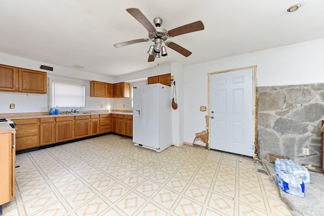 kitchen with ceiling fan, white fridge with ice dispenser, and sink