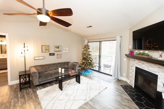 living room featuring a stone fireplace, ceiling fan, dark hardwood / wood-style floors, and lofted ceiling