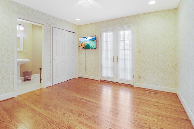 empty room featuring french doors, ceiling fan, and light wood-type flooring