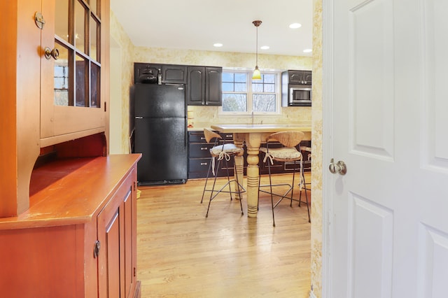 kitchen with black refrigerator and light hardwood / wood-style flooring