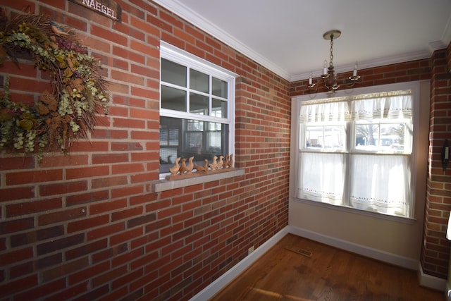 unfurnished dining area with dark wood-type flooring, ornamental molding, and brick wall