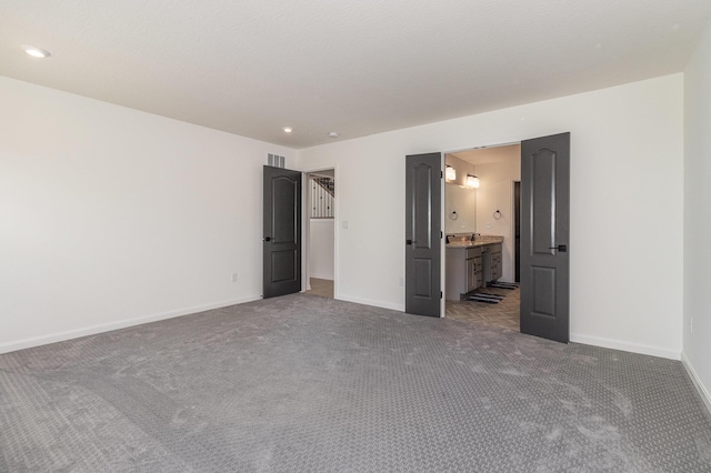 unfurnished bedroom featuring ensuite bathroom and carpet floors