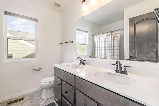 bathroom featuring vanity, toilet, curtained shower, and a healthy amount of sunlight