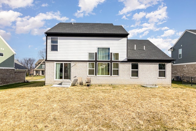 back of house with central air condition unit and a yard