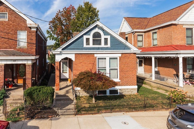 view of front of property with a fenced front yard, a porch, and brick siding