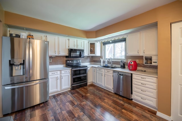 kitchen featuring appliances with stainless steel finishes, tasteful backsplash, dark wood-type flooring, sink, and white cabinetry