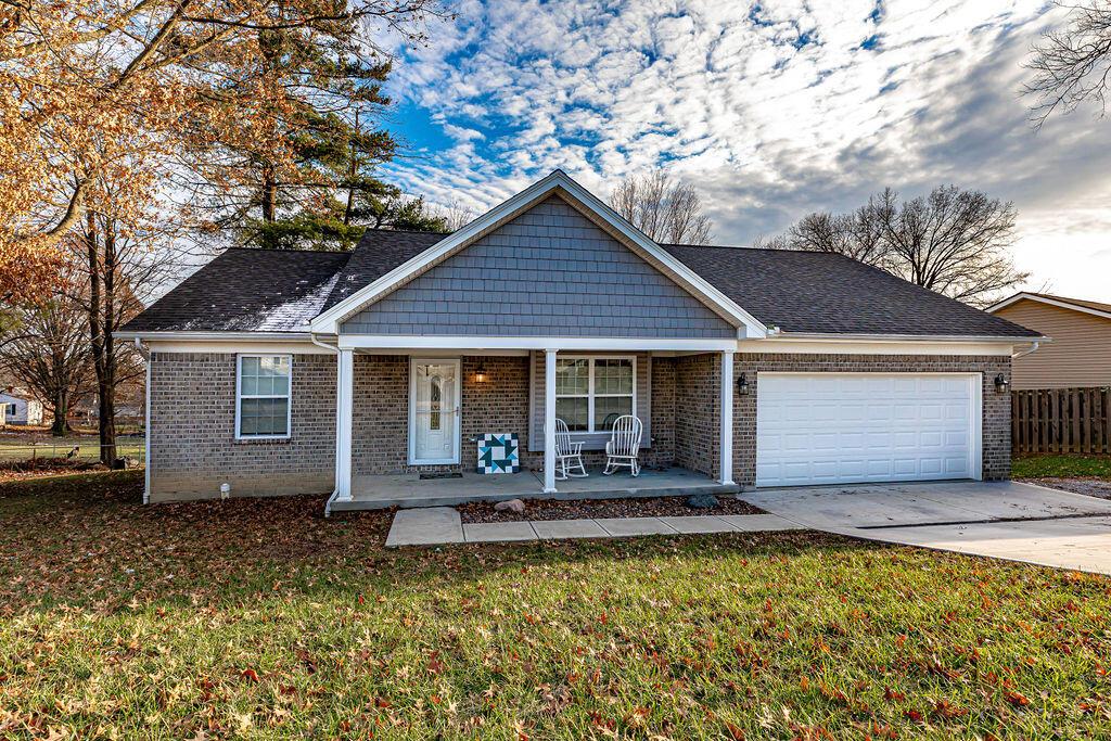 view of front of house featuring covered porch, a garage, and a front lawn