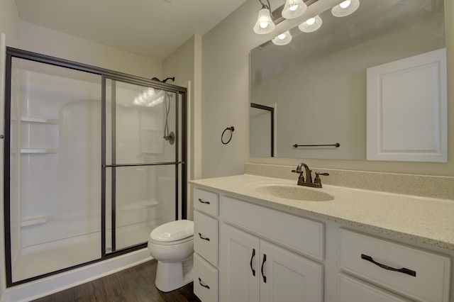 bathroom with a shower with door, vanity, wood-type flooring, and toilet