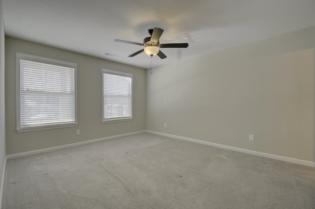 empty room featuring ceiling fan and light colored carpet