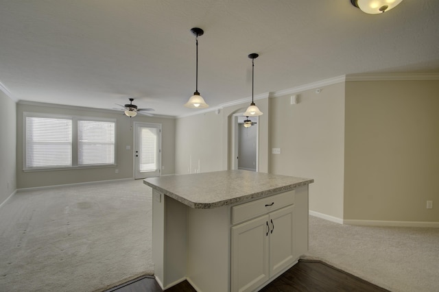 kitchen with ornamental molding, light colored carpet, ceiling fan, white cabinetry, and hanging light fixtures