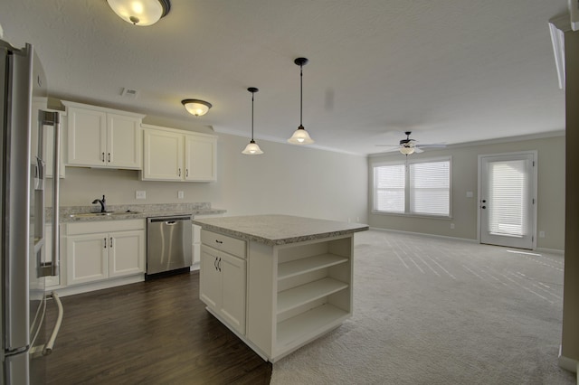 kitchen featuring sink, hanging light fixtures, a kitchen island, white cabinets, and appliances with stainless steel finishes