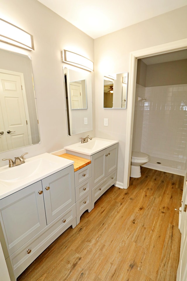 bathroom featuring a shower, hardwood / wood-style floors, vanity, and toilet