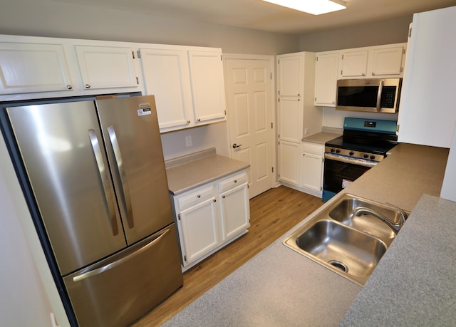 kitchen with sink, white cabinets, stainless steel appliances, and light hardwood / wood-style flooring