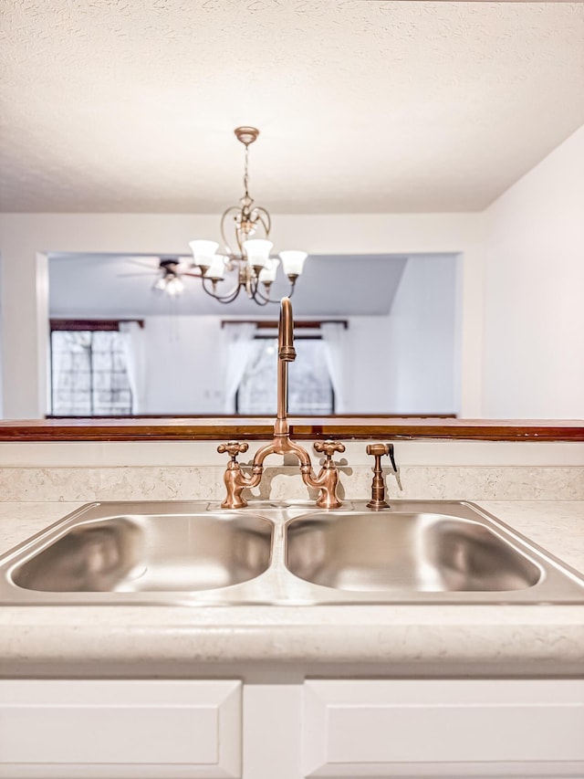 room details featuring a textured ceiling, decorative light fixtures, a notable chandelier, and sink