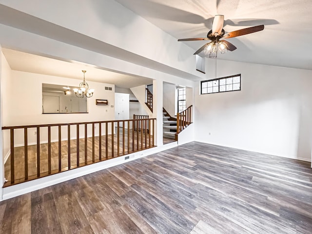 empty room featuring hardwood / wood-style floors, ceiling fan with notable chandelier, and lofted ceiling