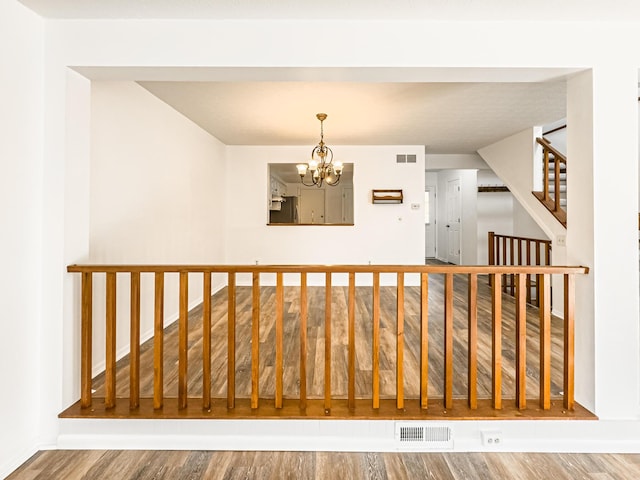 stairs featuring a notable chandelier and wood-type flooring