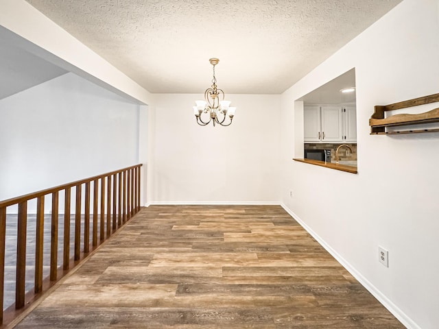 interior space featuring hardwood / wood-style floors, a textured ceiling, an inviting chandelier, and sink