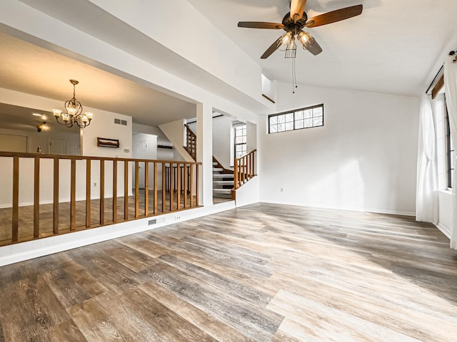 unfurnished room with ceiling fan with notable chandelier, wood-type flooring, and vaulted ceiling