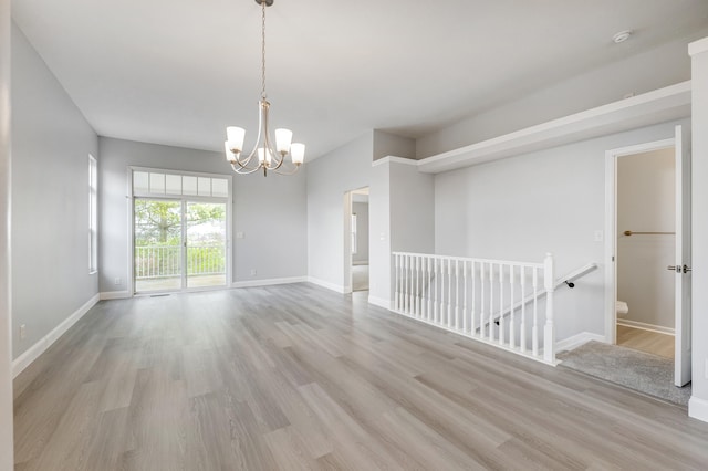 empty room featuring light wood-type flooring and an inviting chandelier