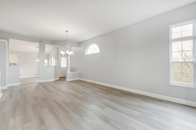 unfurnished dining area featuring light wood-type flooring, vaulted ceiling, and a notable chandelier