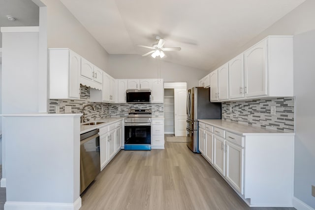 kitchen featuring sink, stainless steel appliances, lofted ceiling, decorative backsplash, and white cabinets