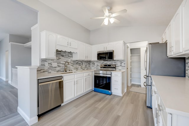 kitchen with ceiling fan, sink, vaulted ceiling, white cabinets, and appliances with stainless steel finishes