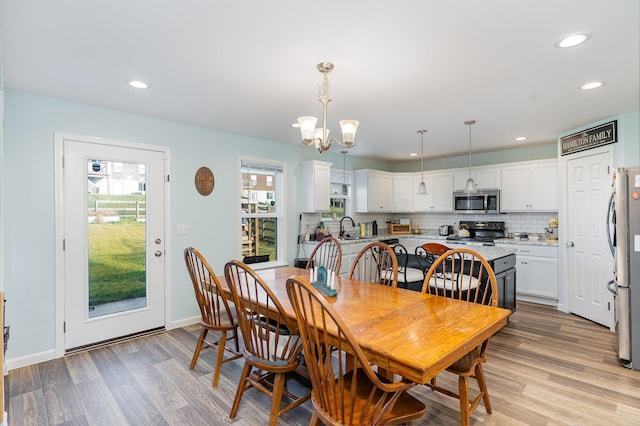 dining room with light hardwood / wood-style flooring, an inviting chandelier, and sink