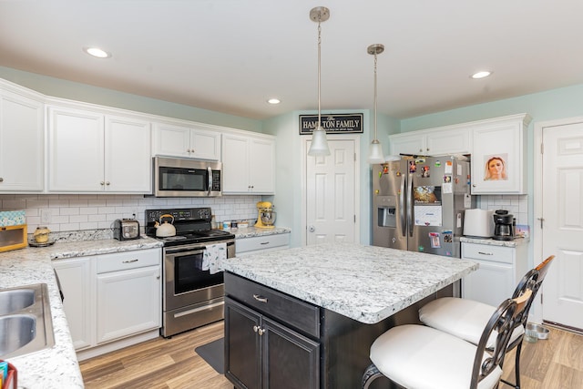 kitchen with white cabinetry, stainless steel appliances, and hanging light fixtures