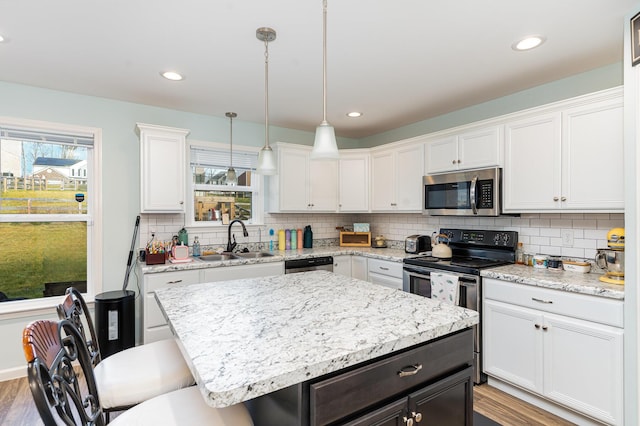 kitchen featuring a center island, white cabinets, stainless steel appliances, and decorative light fixtures