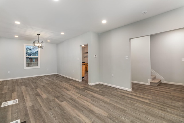 spare room with dark hardwood / wood-style floors and an inviting chandelier