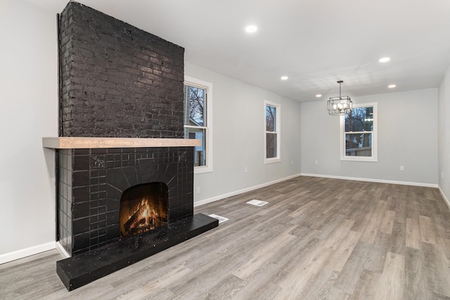 unfurnished living room with hardwood / wood-style floors and a brick fireplace