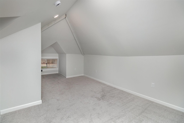 additional living space featuring light colored carpet and vaulted ceiling