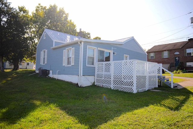 view of side of home featuring a lawn and central AC unit