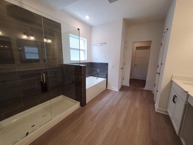 full bathroom featuring a bath, wood finished floors, vanity, a shower stall, and baseboards