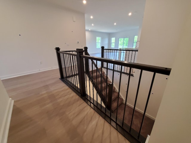stairway featuring wood finished floors, recessed lighting, and baseboards