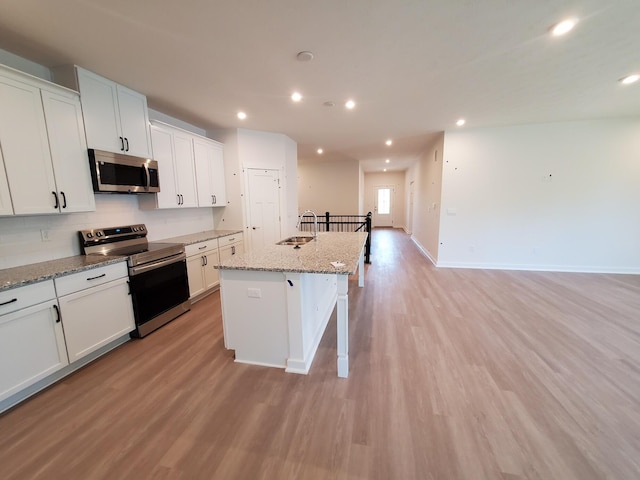 kitchen with stainless steel appliances, light wood-style flooring, an island with sink, recessed lighting, and a kitchen breakfast bar