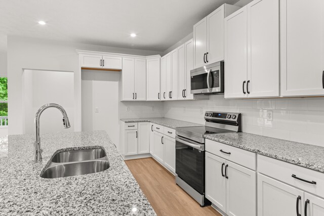 2516 Winners Post Way, Burlington, KY 41005 - kitchen with appliances with stainless steel finishes, a sink, decorative backsplash, white cabinetry, and light wood-style floors