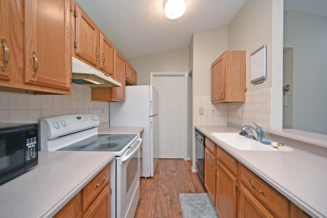 kitchen with backsplash, dark wood-type flooring, black appliances, sink, and vaulted ceiling